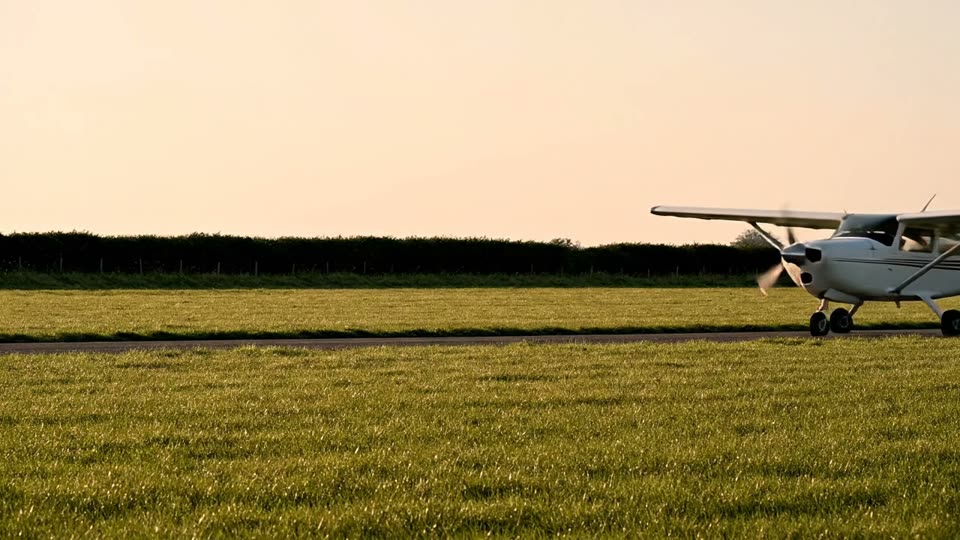 A training aircraft crossing a grass airfield